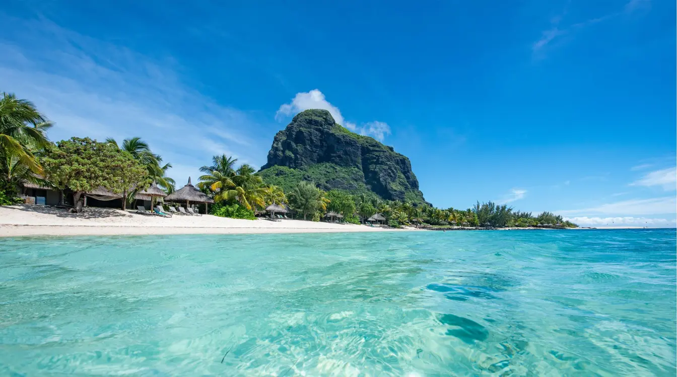 Vue sur la plage du Morne à l'île Maurice, avec son lagon turquoise, son sable blanc et la montagne du Morne Brabant en arrière-plan.