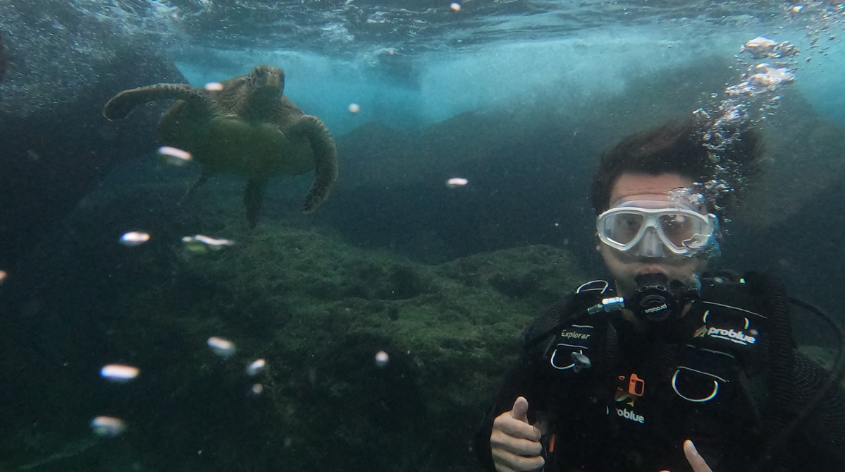 Scuba diver posing next to a sea turtle in the waters of Xiaoliuqiu