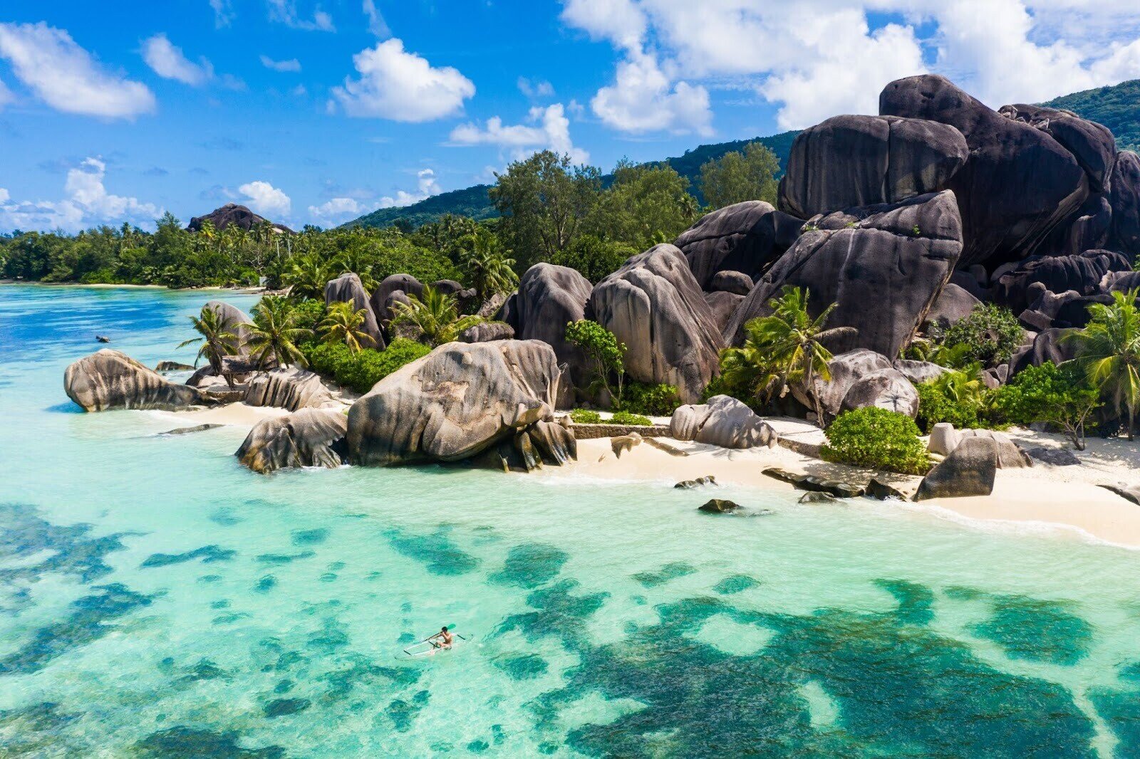 Eine große Felsformation an einem sonnigen Strand auf der Insel La Digue zur Regenzeit auf den Seychellen.