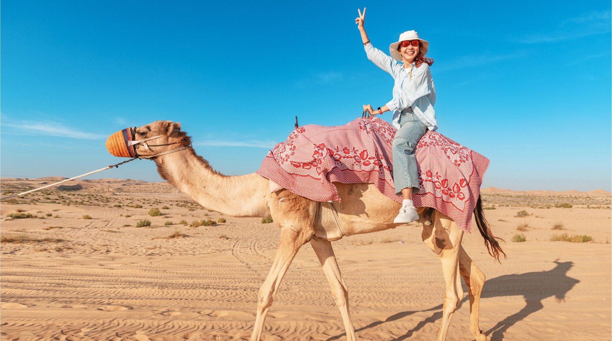 Jovem com camelo no deserto de Dubai