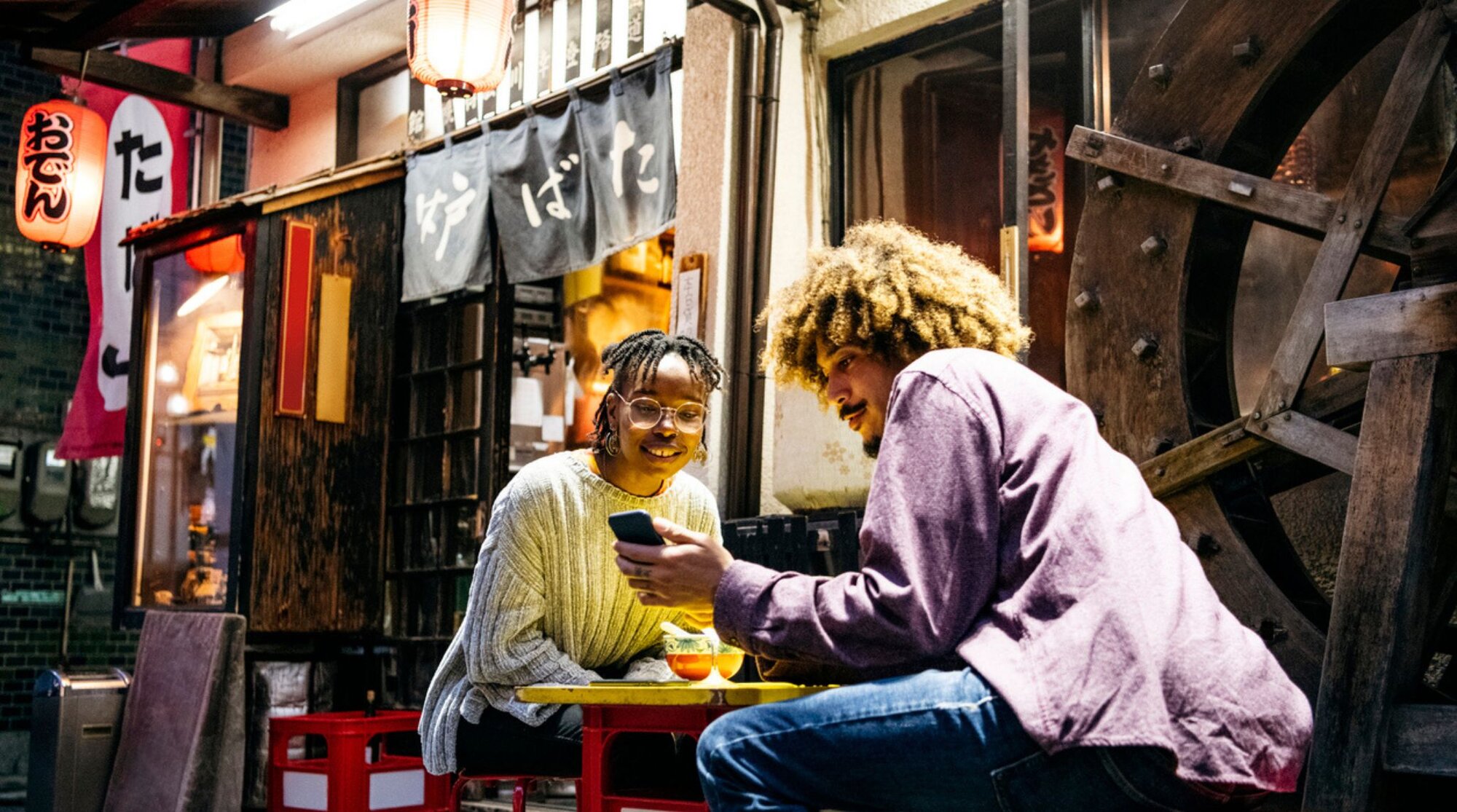 Zwei junge Leute sitzen in Japan in einem Restaurant und benutzen Apps.