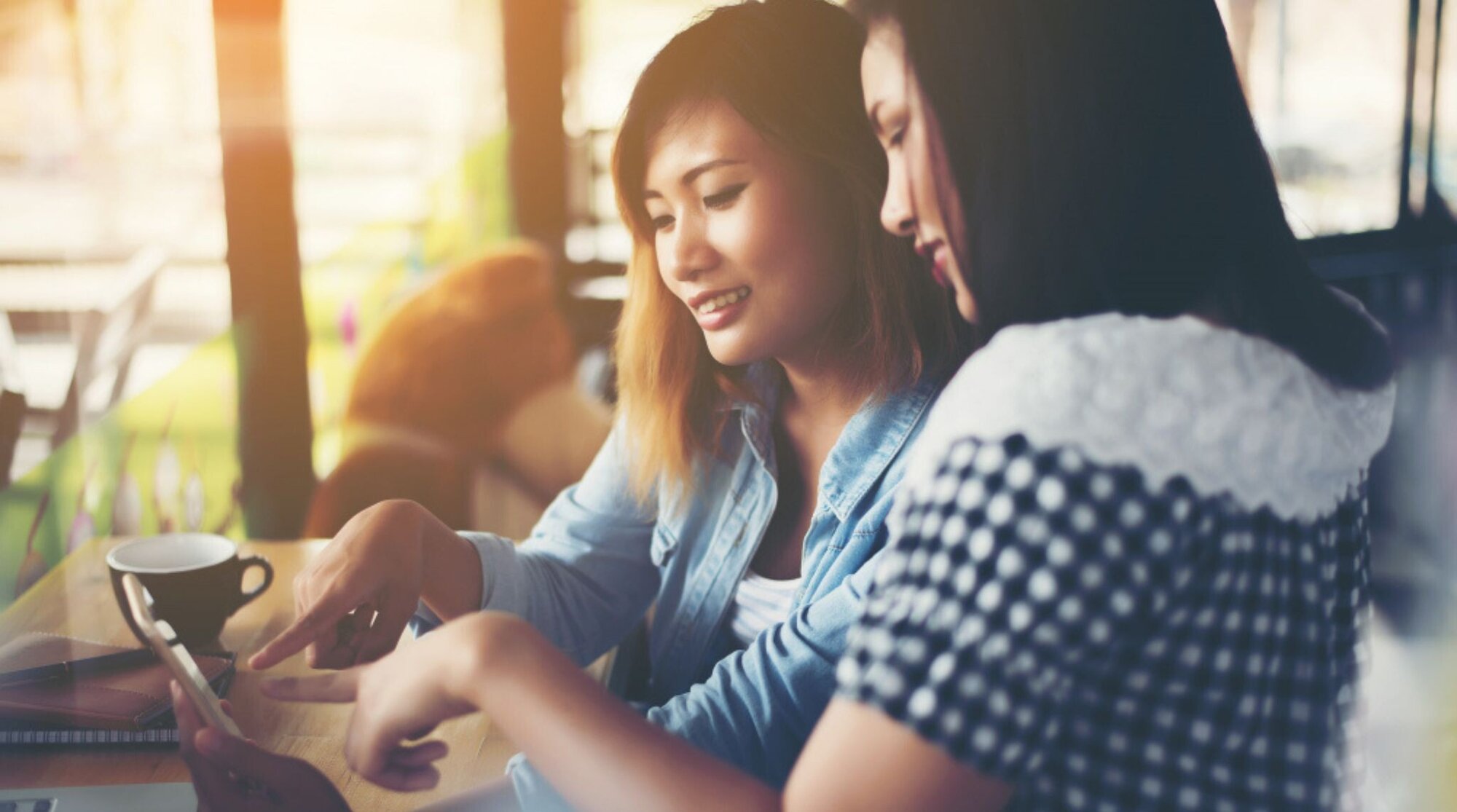 友達とスマホを見て談笑する女性