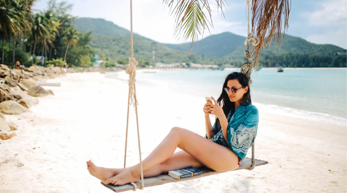 Voyageuse utilisant son téléphone sur une plage de Koh Phangan en Thaïlande.