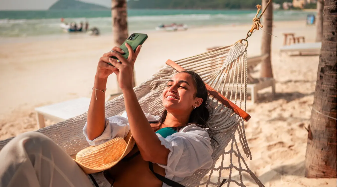 Voyageuse souriante prenant un selfie sur une plage de Zanzibar avec son smartphone connecté à internet