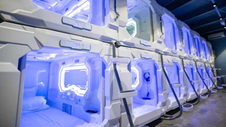 Futuristic capsule hotel in Tokyo with beds stacked neatly on top of each other, glowing in soft purple light to create a sleek, space-age feel — showcasing Japan’s diverse and affordable sleeping options for Tokyo Game Show attendees.