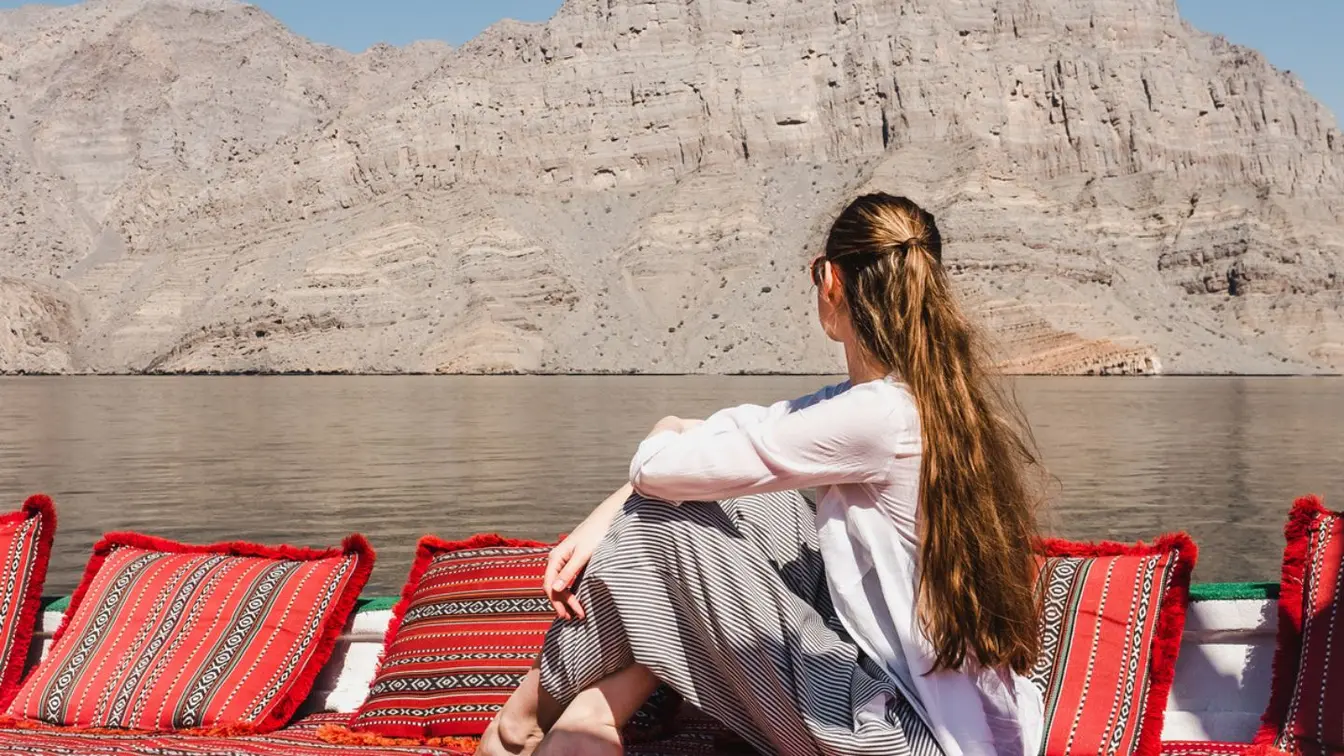 Voyageuse assise dans un bateau dans les fjords d’Oman.