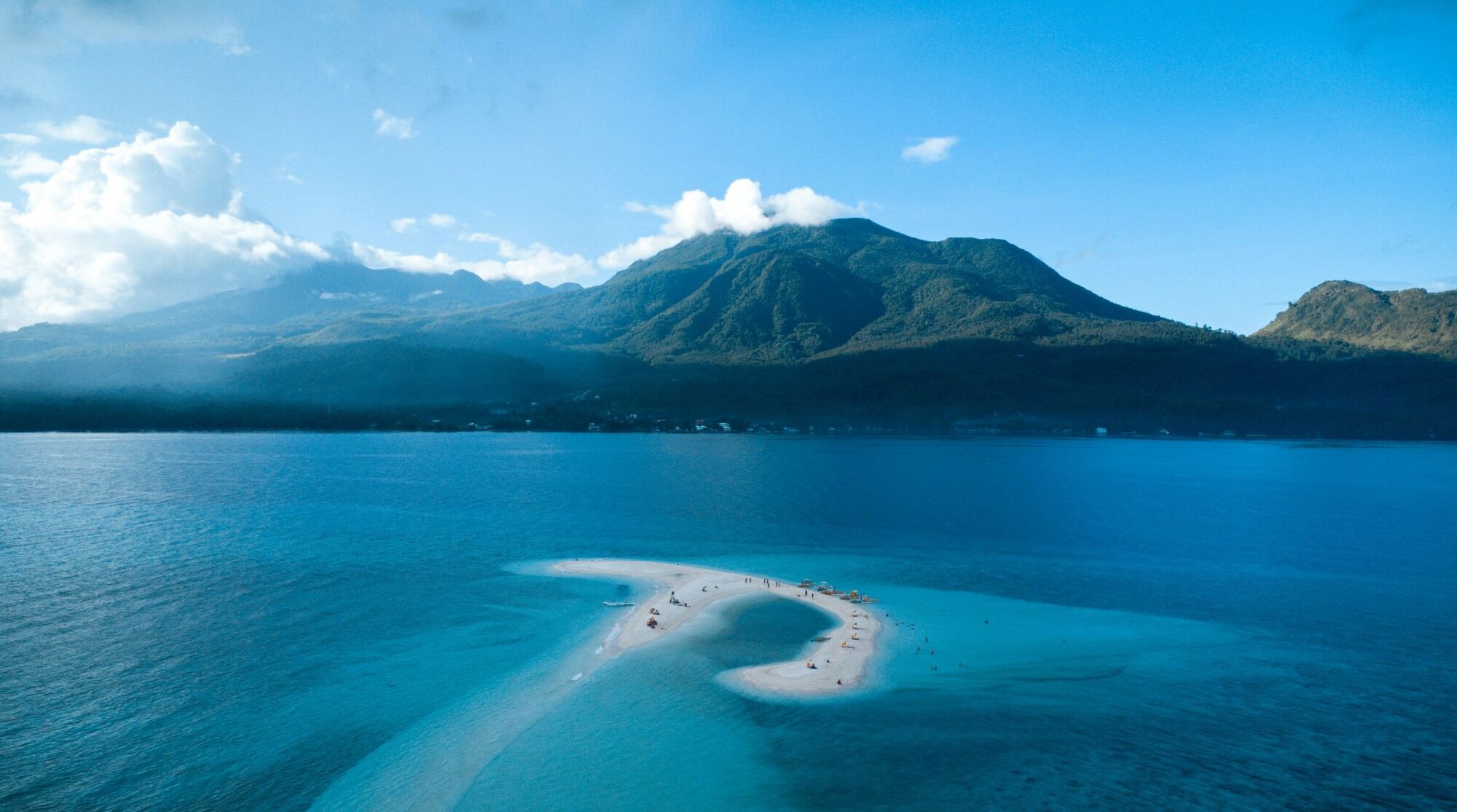 Aerial view of the White Island sandbar, with the volcanic peaks of Camiguin Island towering behind it.