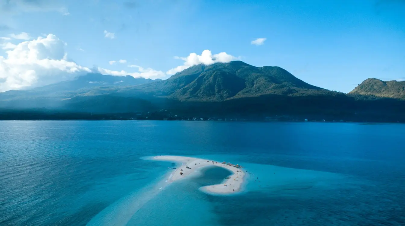 Aerial view of the White Island sandbar, with the volcanic peaks of Camiguin Island towering behind it.