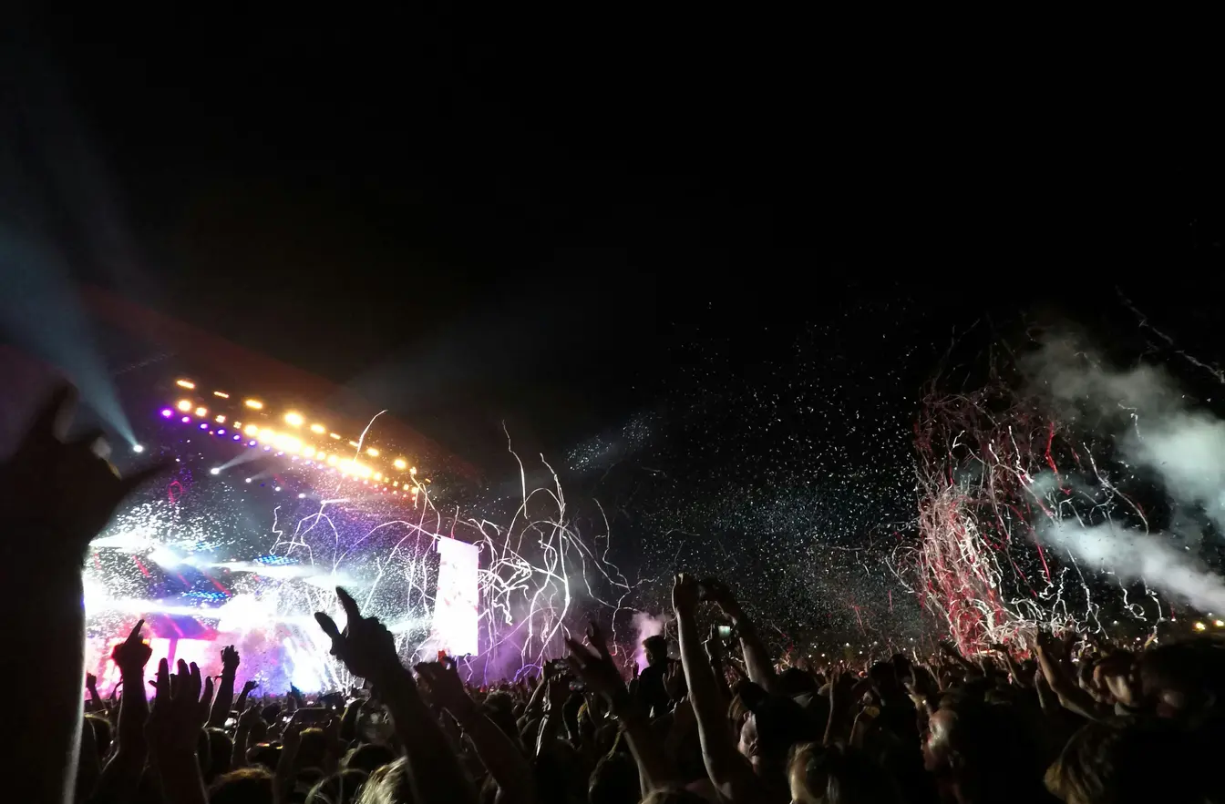 Lit-up stage with confetti and raised hands at Reading Festival in England