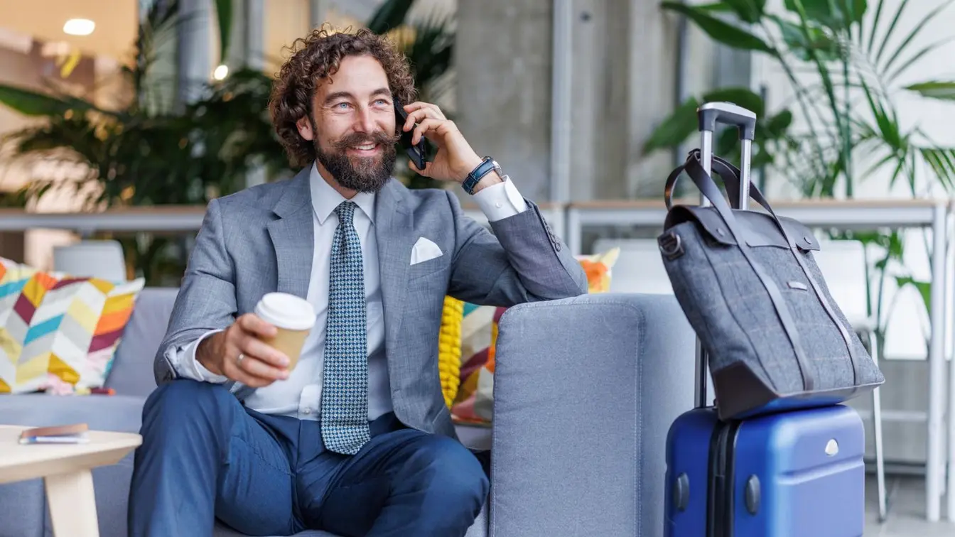 Voyageur d’affaires téléphonant dans un salon d’aéroport en attendant son vol.