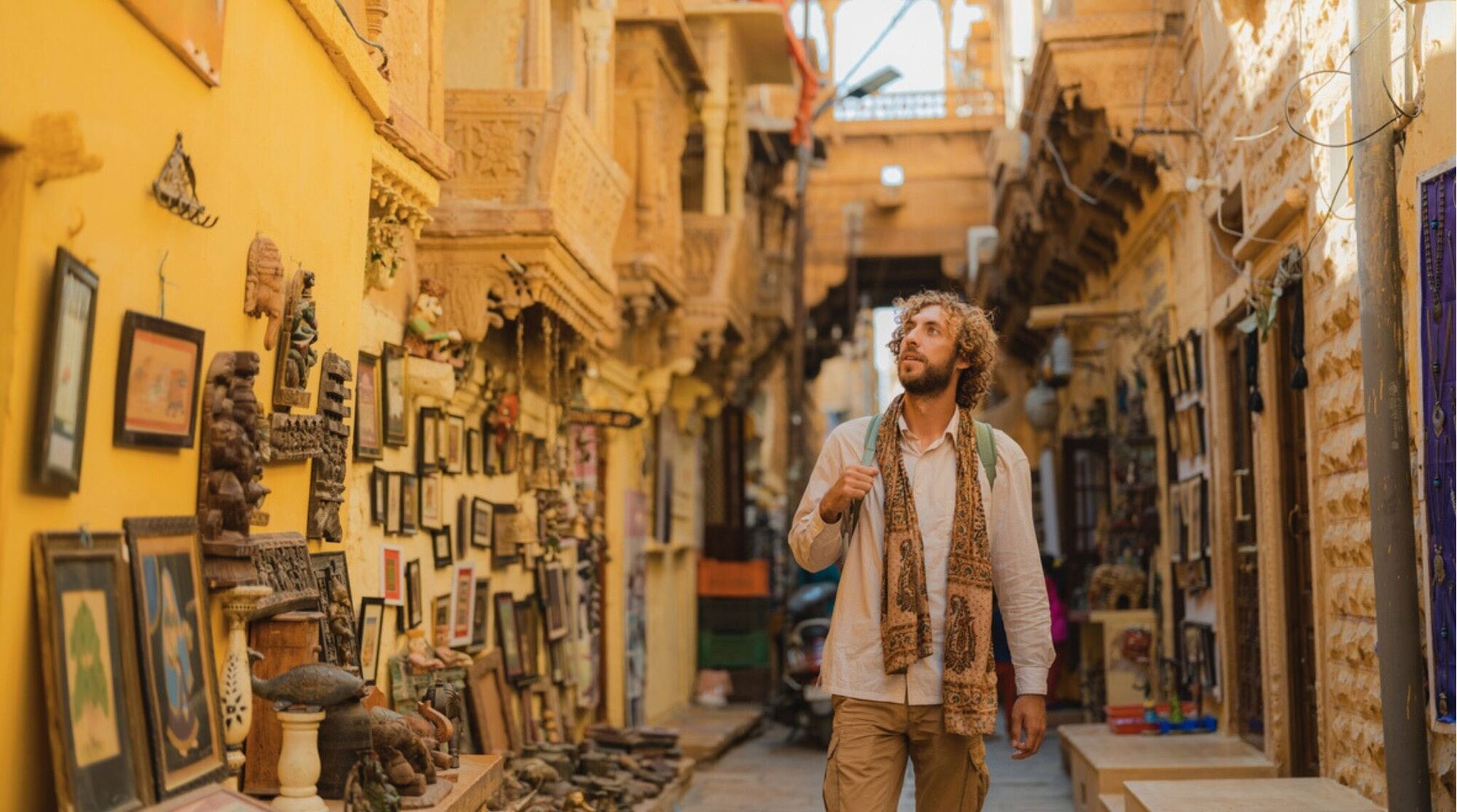 Hombre caminando por una calle estrecha con tiendas y fachadas antiguas en un casco histórico.