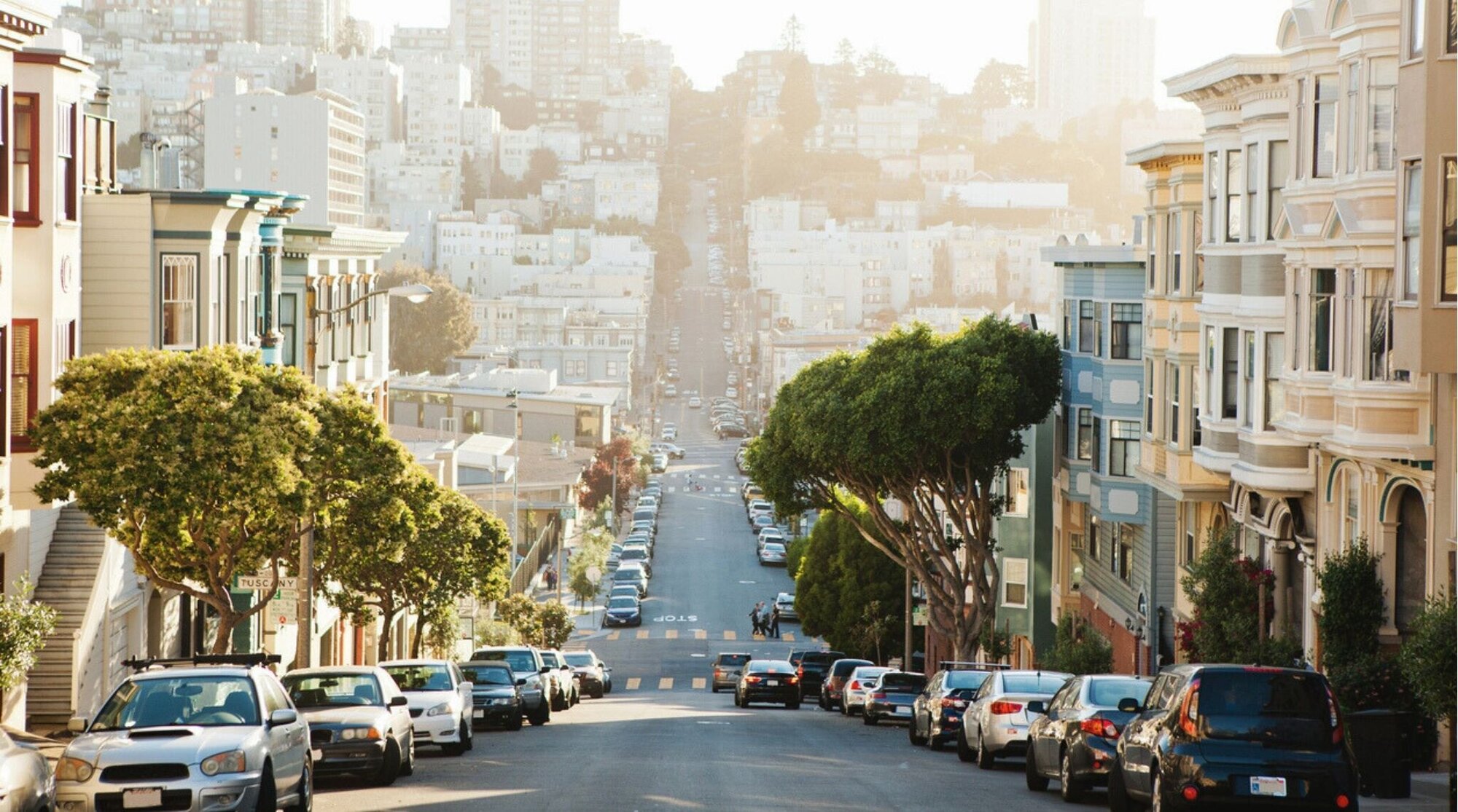 Vista de una calle empinada en San Francisco con casas victorianas y coches estacionados en la colina.