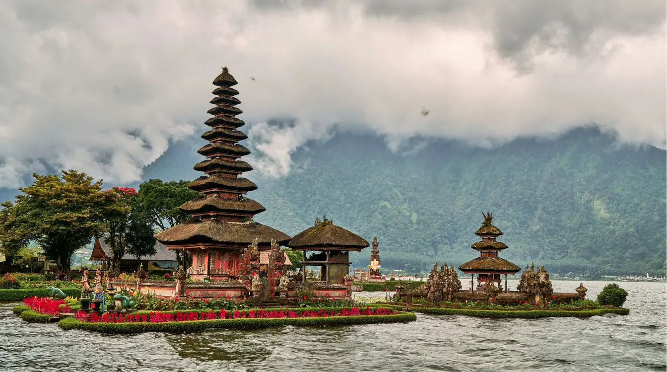 View of Bedugul’s Ulun Danu Beratan Temple on Lake Beratan in front of a misty mountain backdrop.