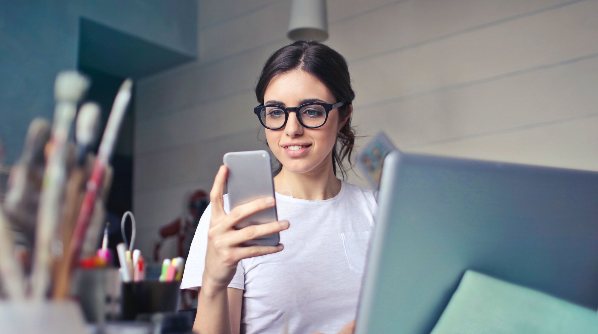 נערה עובדת על מחשב נייד ומסתכלת על טלפון חכם