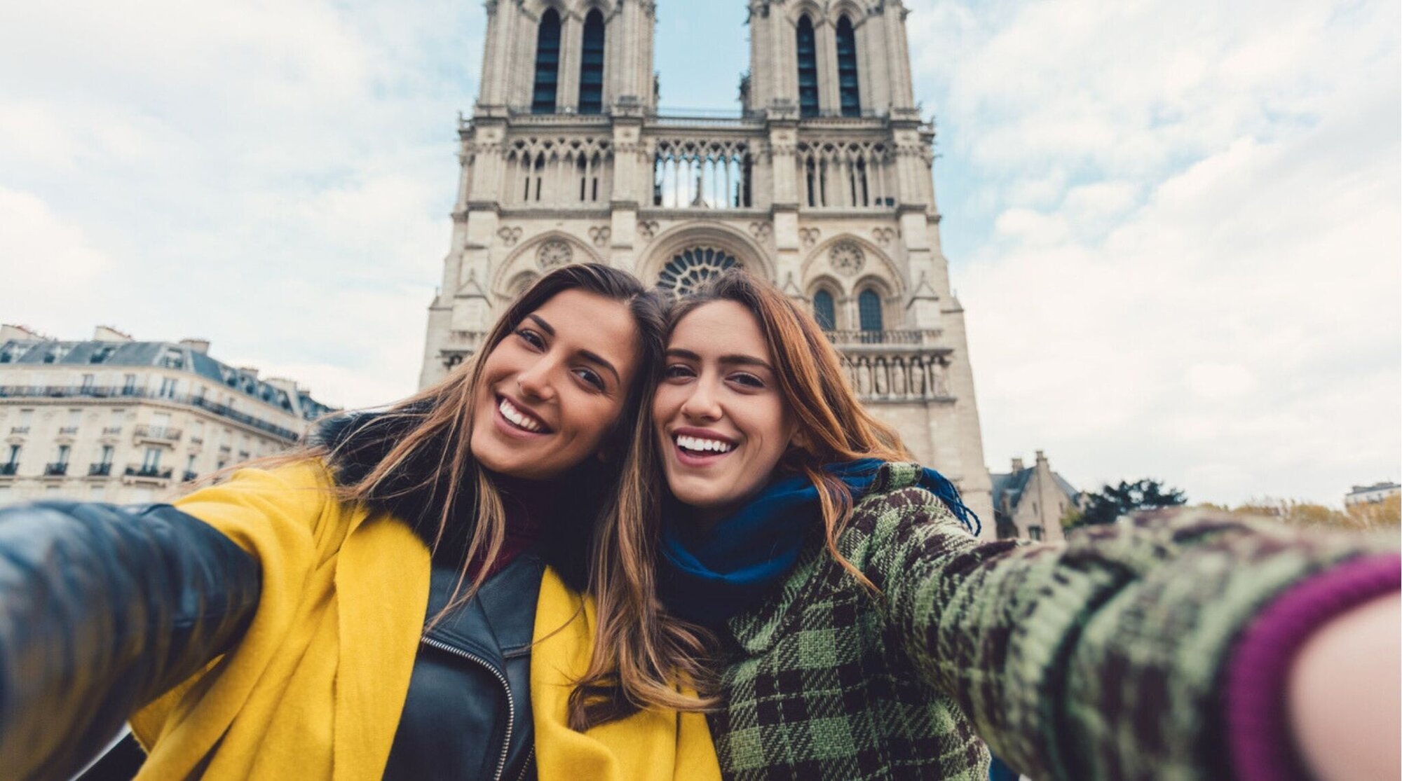 Amigas tomando selfie en París durante el invierno con ropa abrigadora y ambiente festivo.