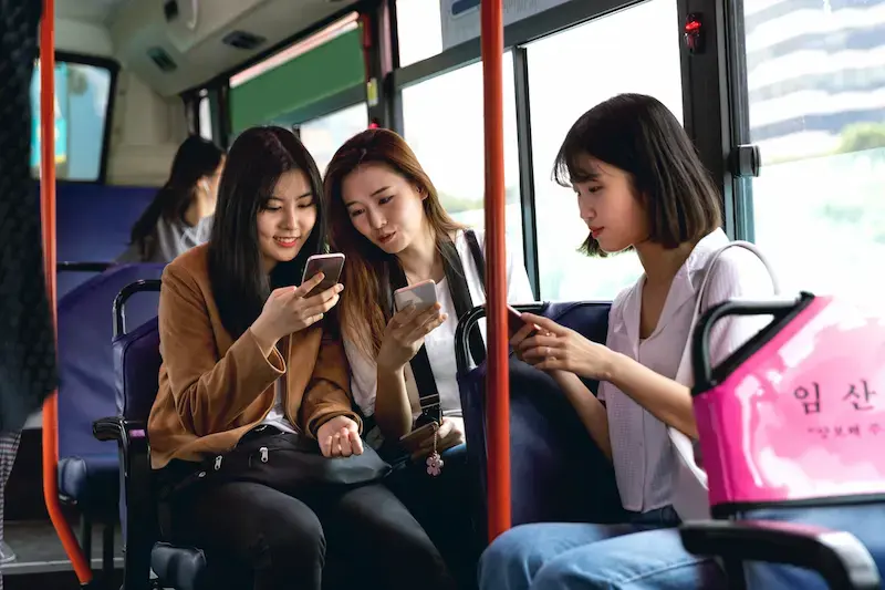 韓国のバスでスマホを見ながら談笑する三人の女性