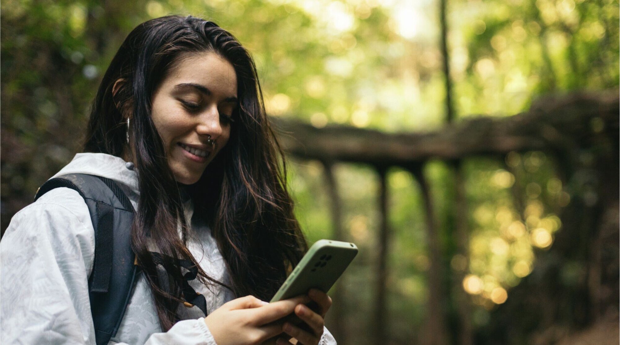 Joven utilizando su teléfono celular en un paisaje de Costa Rica.