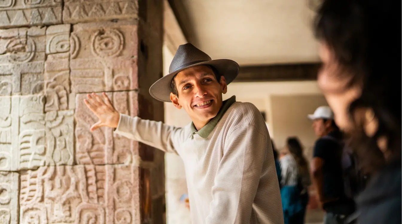 Guía explicando relieves en Teotihuacán a una viajera durante un recorrido