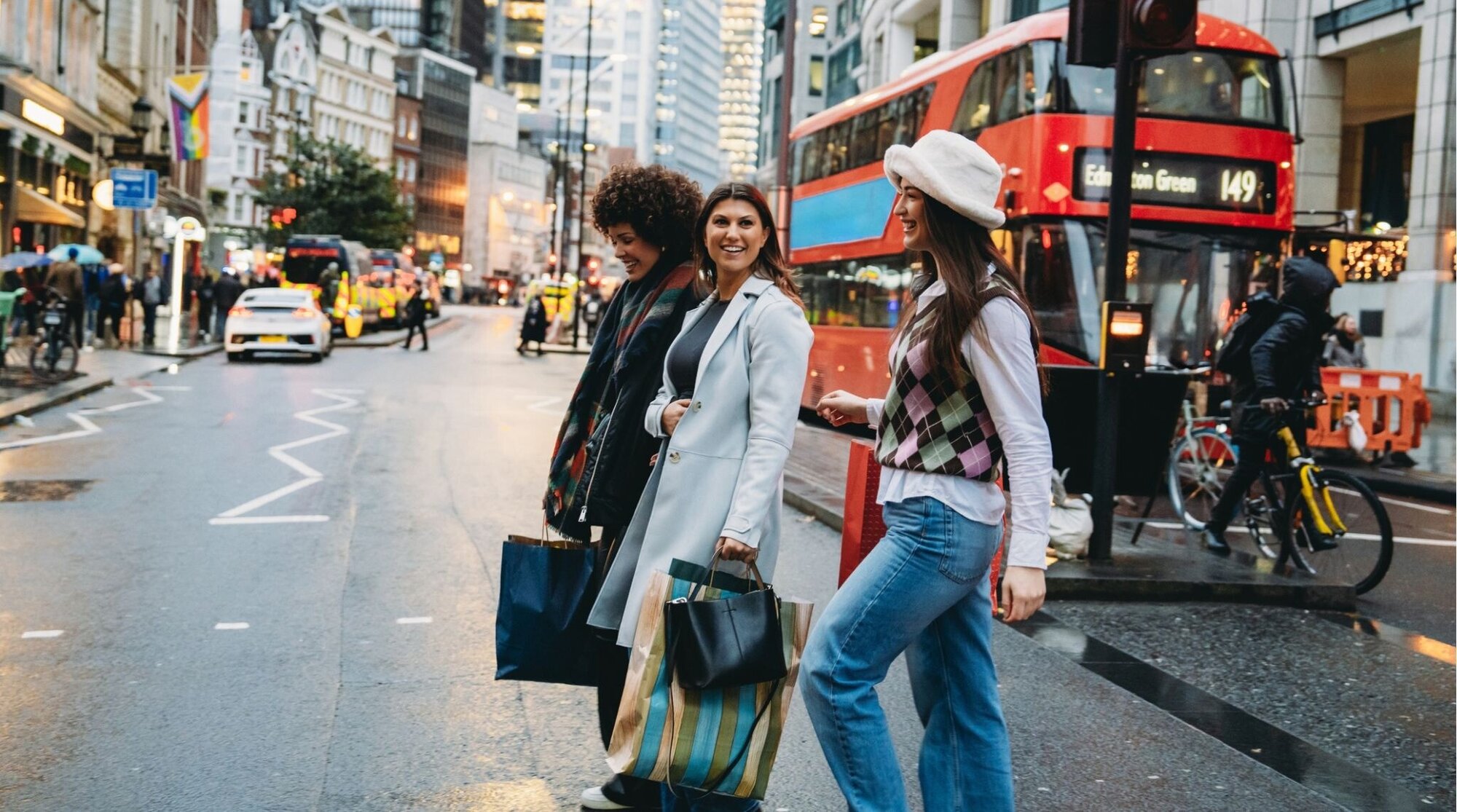 Três, mulheres jovens, andar, ligado, faixa de pedestres, em, londres, com, sacos compras