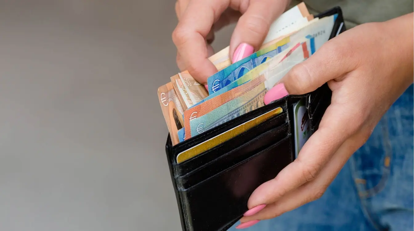 Femme tenant des billets en euros pour préparer le budget de son voyage seule.