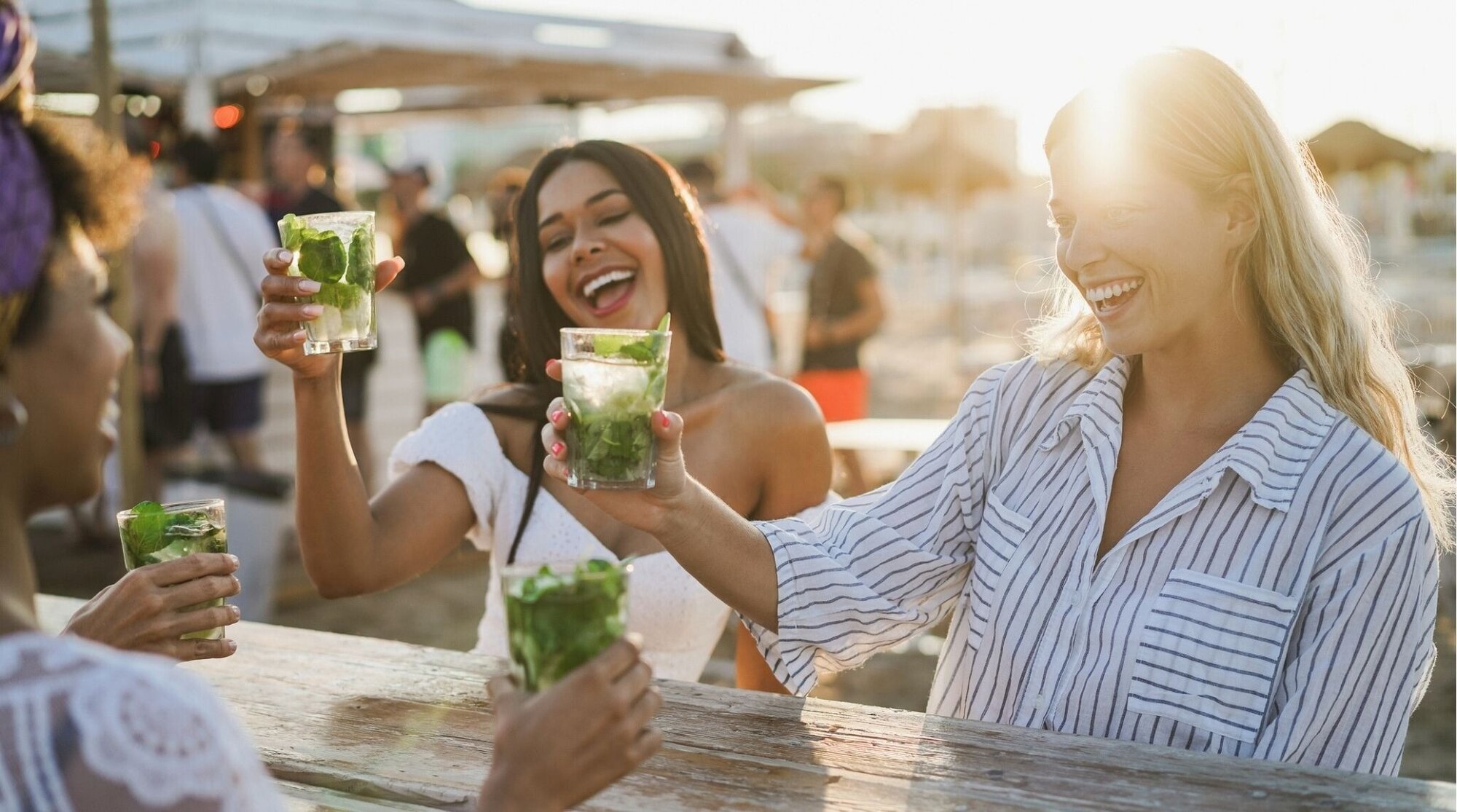Amigas brindando con cócteles en un chiringuito de playa, vacaciones.