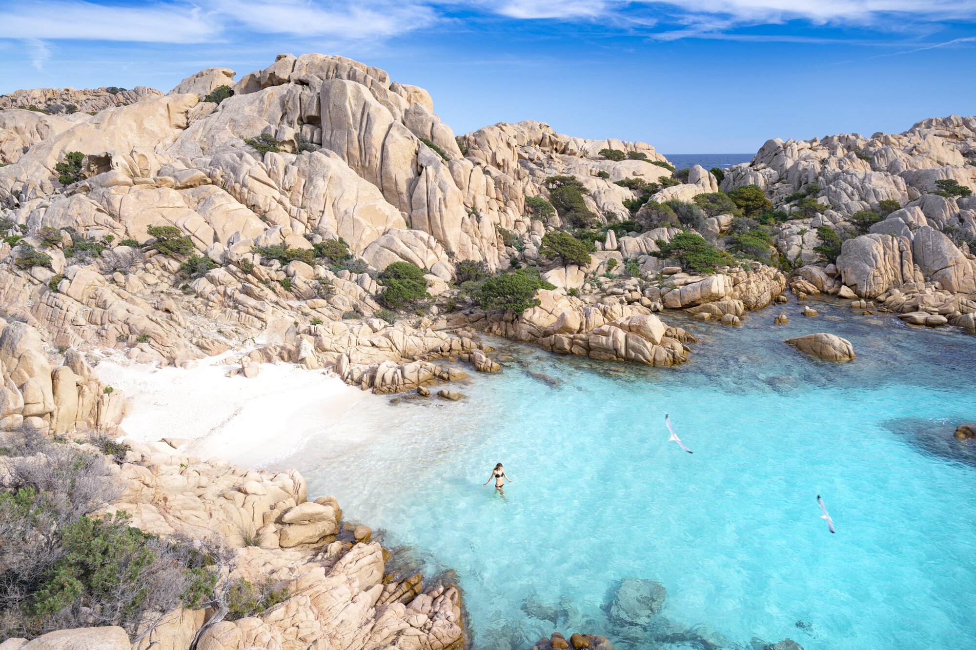 Eine Frau, die an einem abgelegenen Strand auf Madallena, Sardinien, Italien, schwimmen geht
