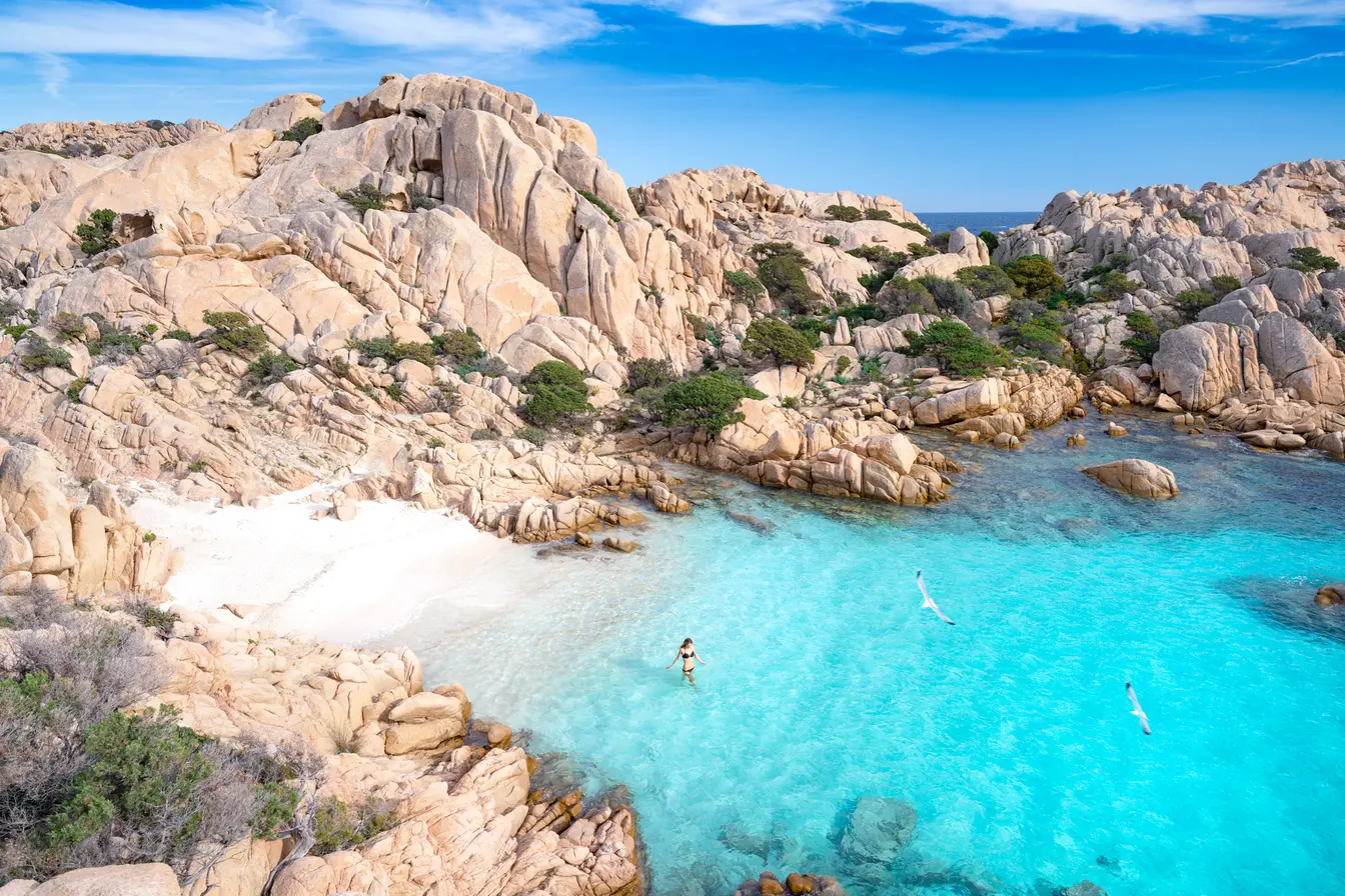 Eine Frau, die an einem abgelegenen Strand auf Madallena, Sardinien, Italien, schwimmen geht