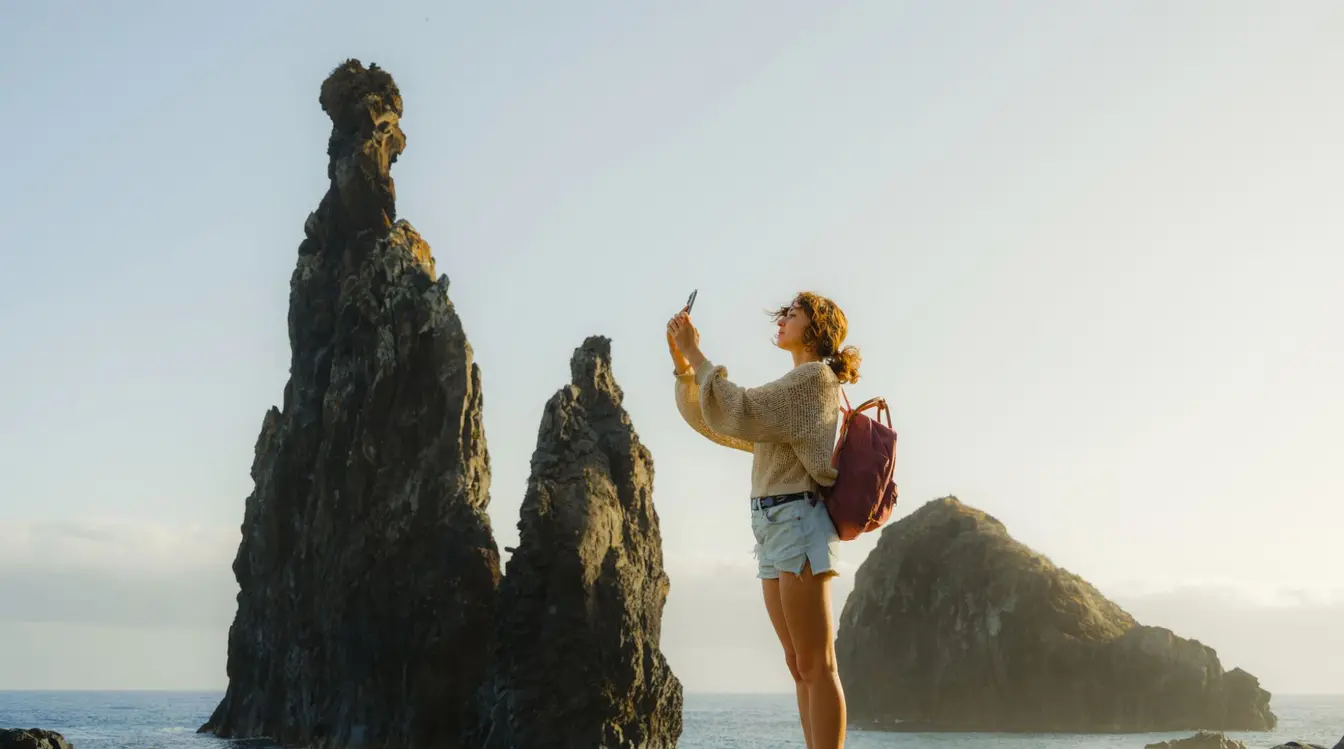 Frau fotografiert mit Smartphone Felsformationen an der Küste auf der Insel Madeira