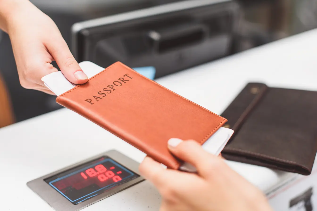  Una persona entregando su pasaporte y otra documentación de viaje en el mostrador de un aeropuerto para ilustrar el ESTA para EE. UU.