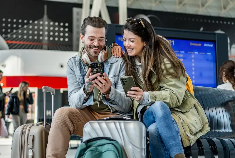 Pareja usando sus celulares en una estación de tren al llegar a Canadá