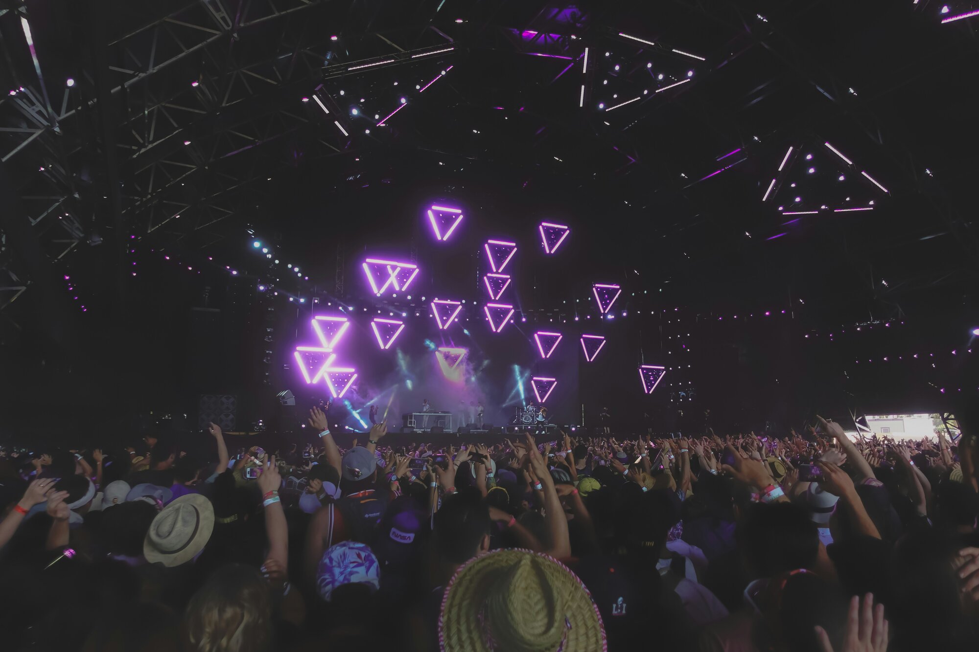 Dark stage lit up with purple triangles and a crowd at Coachella in the US