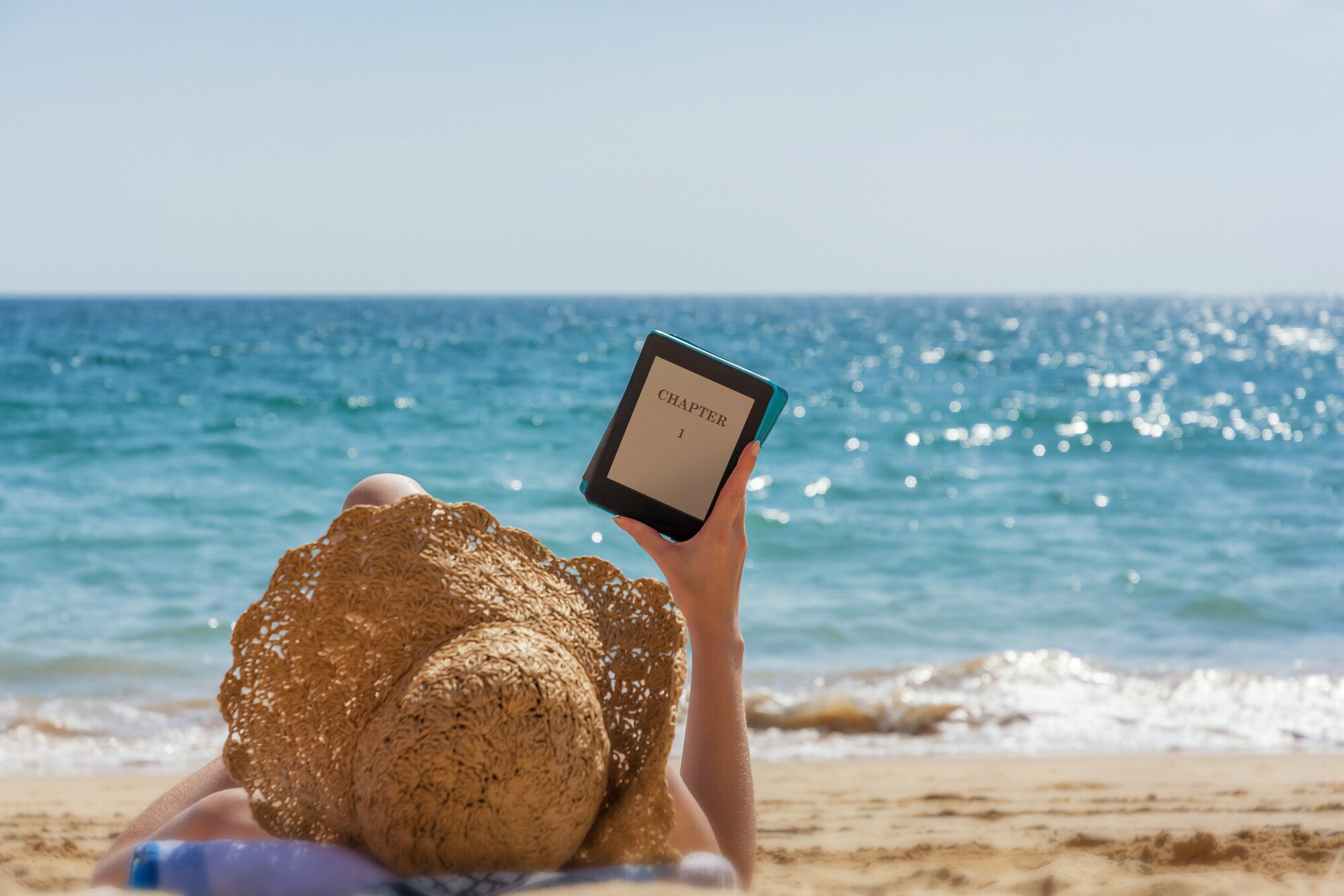 Eine Person am Strand beim Lesen mit e-Book Reader