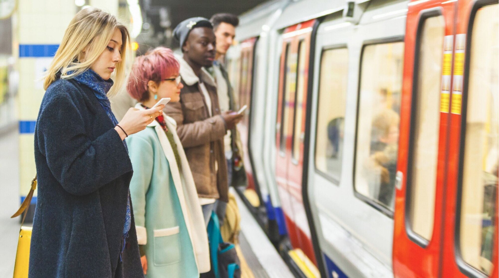 Personas usando sus teléfonos celulares dentro de un vagón del metro de Londres.