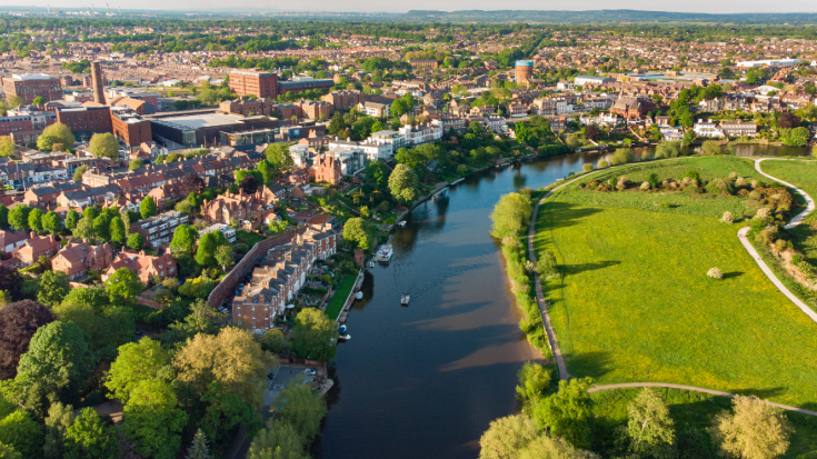 An aerial view of the city of Chester and its surrounding countryside, showing green fields and the Roman cityscape with the River Dee passing through the middle.