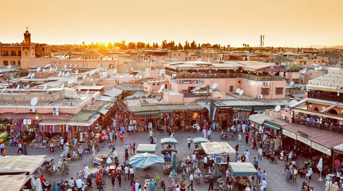 View of the busy Jemaa el-Fnaa market in Marrakech as seen from a rooftop at sunset.
