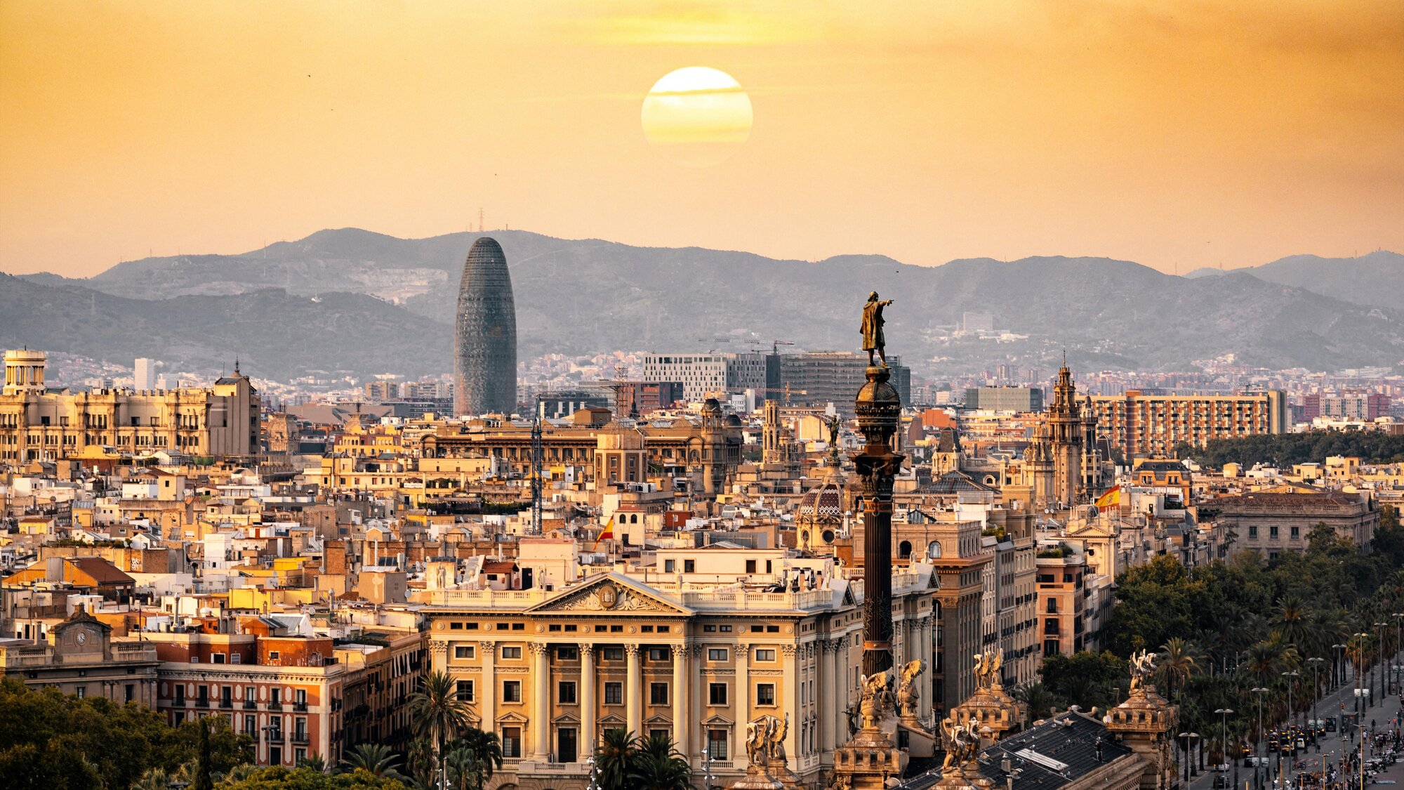 The Barcelona skyline at sunset, showing a charming city against a beautiful mountain backdrop