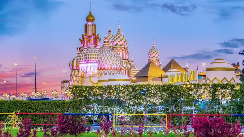 A building topped with Russian-style colourful curved domes at Dubai's Global Village, against a darkening blue sky.