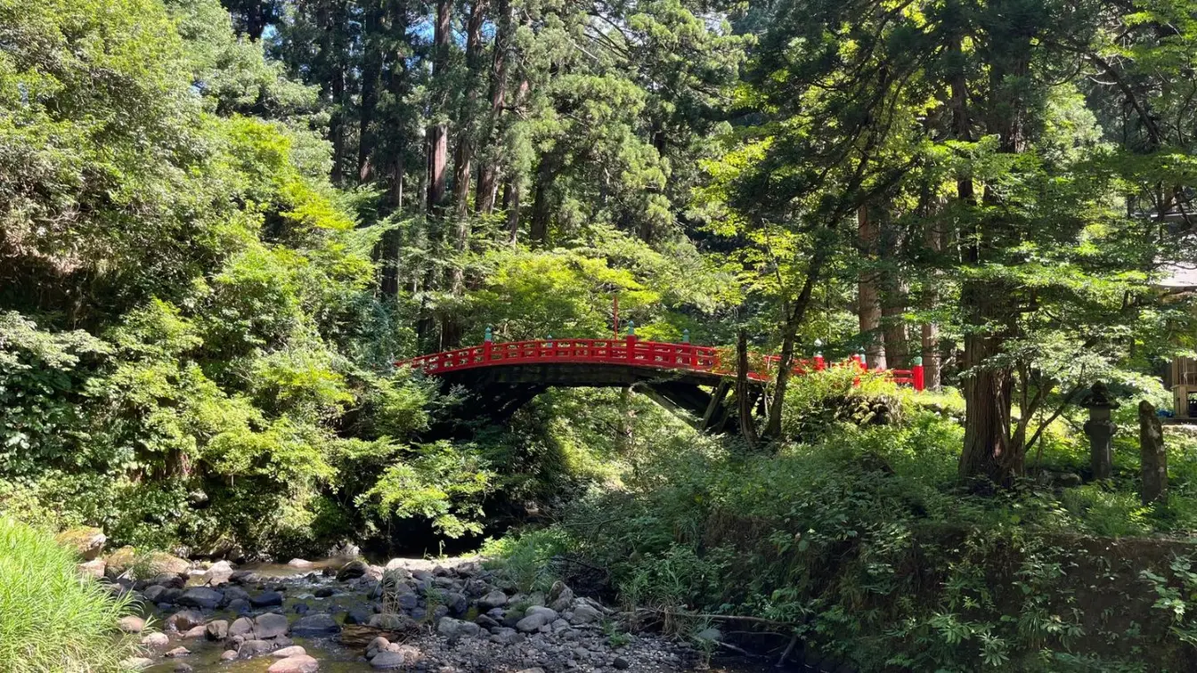 A red bridge crossing the Harai River in the forest near the base of Mount Haguro.