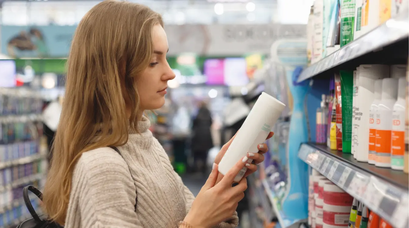 Jovem mulher viajante selecionando produtos de cabelo enquanto faz compras durante sua viagem.