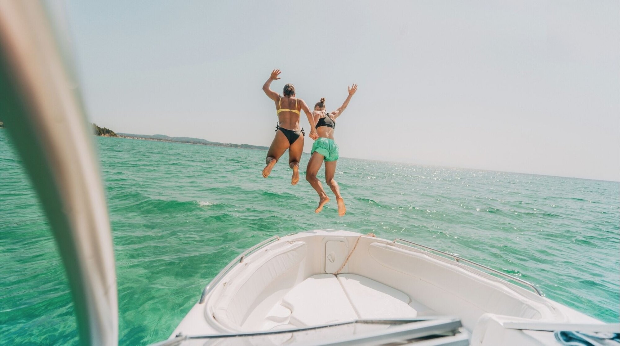 Amigas saltando al mar desde una lancha, adrenalina en vacaciones.
