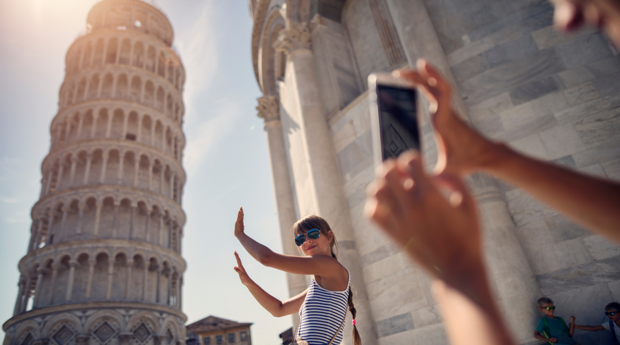 Eine Frau mit Internet in Italien schießt ein Foto von ihrer Freundin vorm Schiefen Turm von Pisa