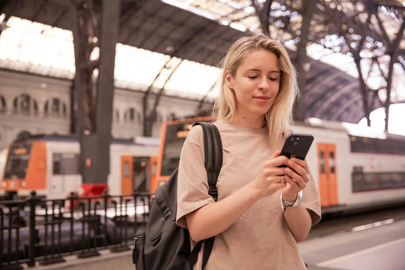 Una persona en una estación de tren mirando el móvil para ilustrar la eSIM con datos ilimitados.