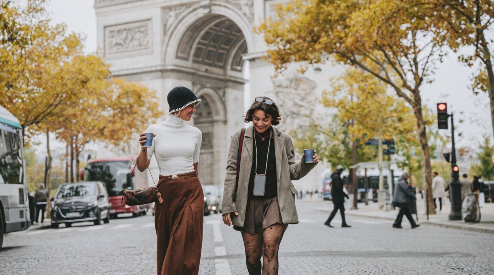 Dos amigas caminando frente al Arco del Triunfo en París; vale la pena una eSIM para viajar.