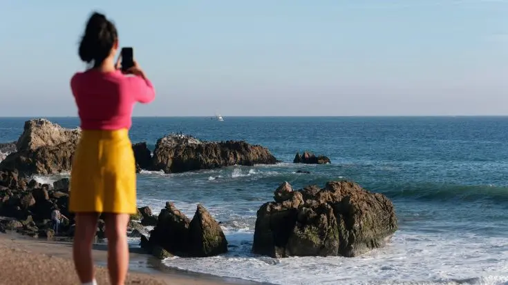 Uma jovem usa seu eSIM ilimitado para tirar e compartilhar fotos do mar.