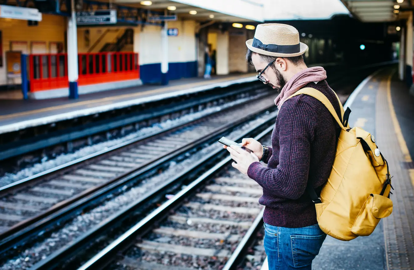  Imagen de una persona utilizando el móvil para consultar los horarios de los trenes.