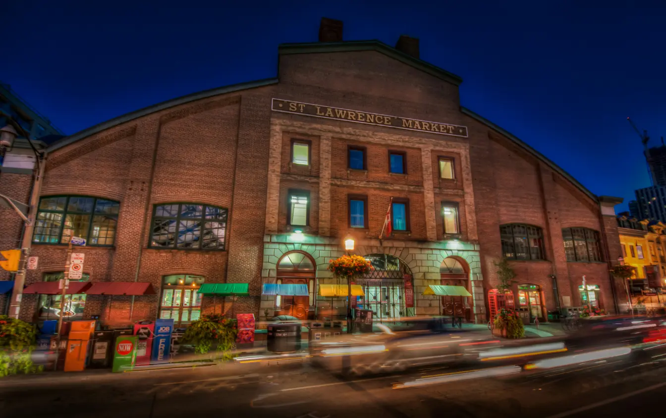 Imagen que muestra el histórico edificio de ladrillo rojo del St. Lawrence Market iluminado durante la noche para ilustrar tips de Toronto.