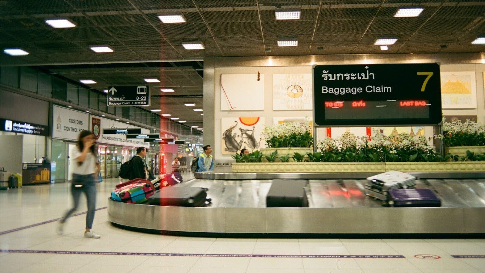 Airport baggage claim with travellers standing by