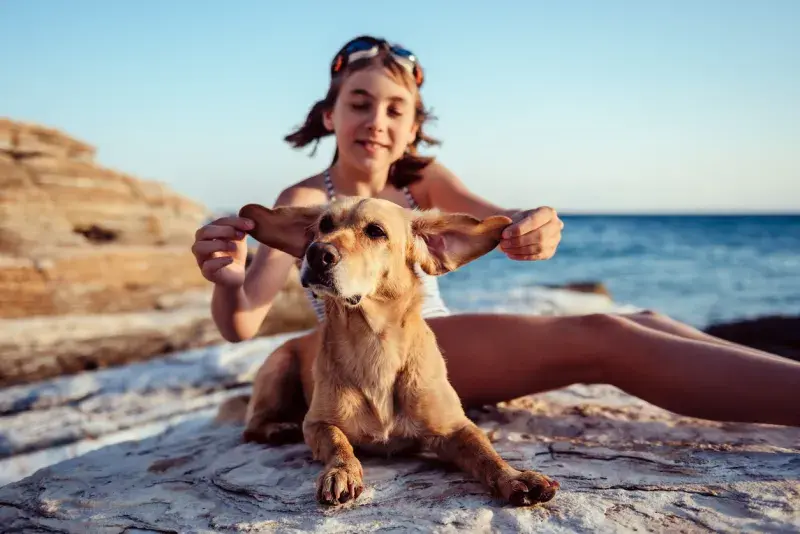 Niña viajera con su perro en la playa de Puerto Escondido durante temporada alta en Semana Santa