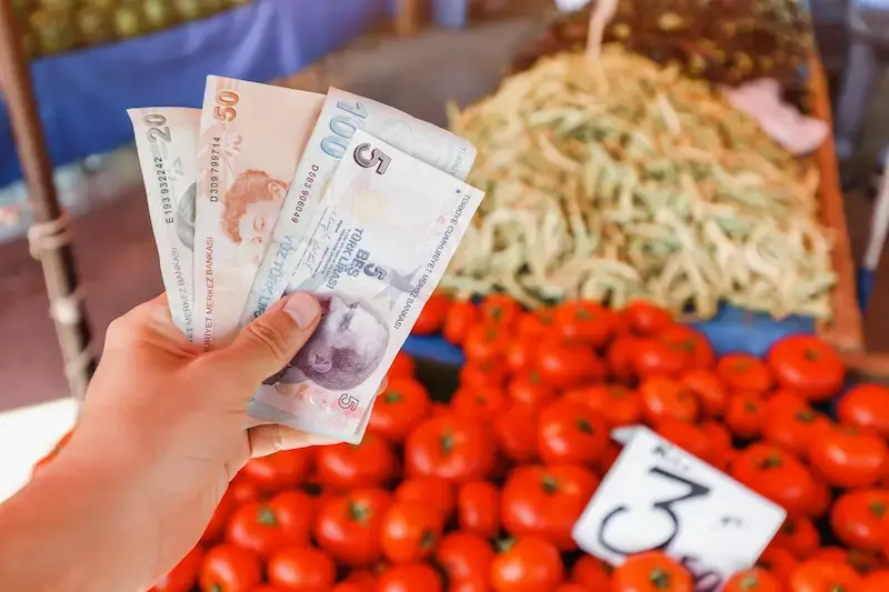 Voyageur payant en livres turques auprès d’un vendeur de street food en Turquie.