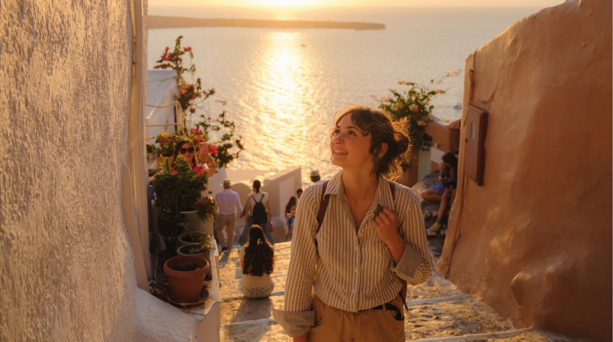 Viajera caminando por Santorini al atardecer; elegir eSIM más barata según días y destino.